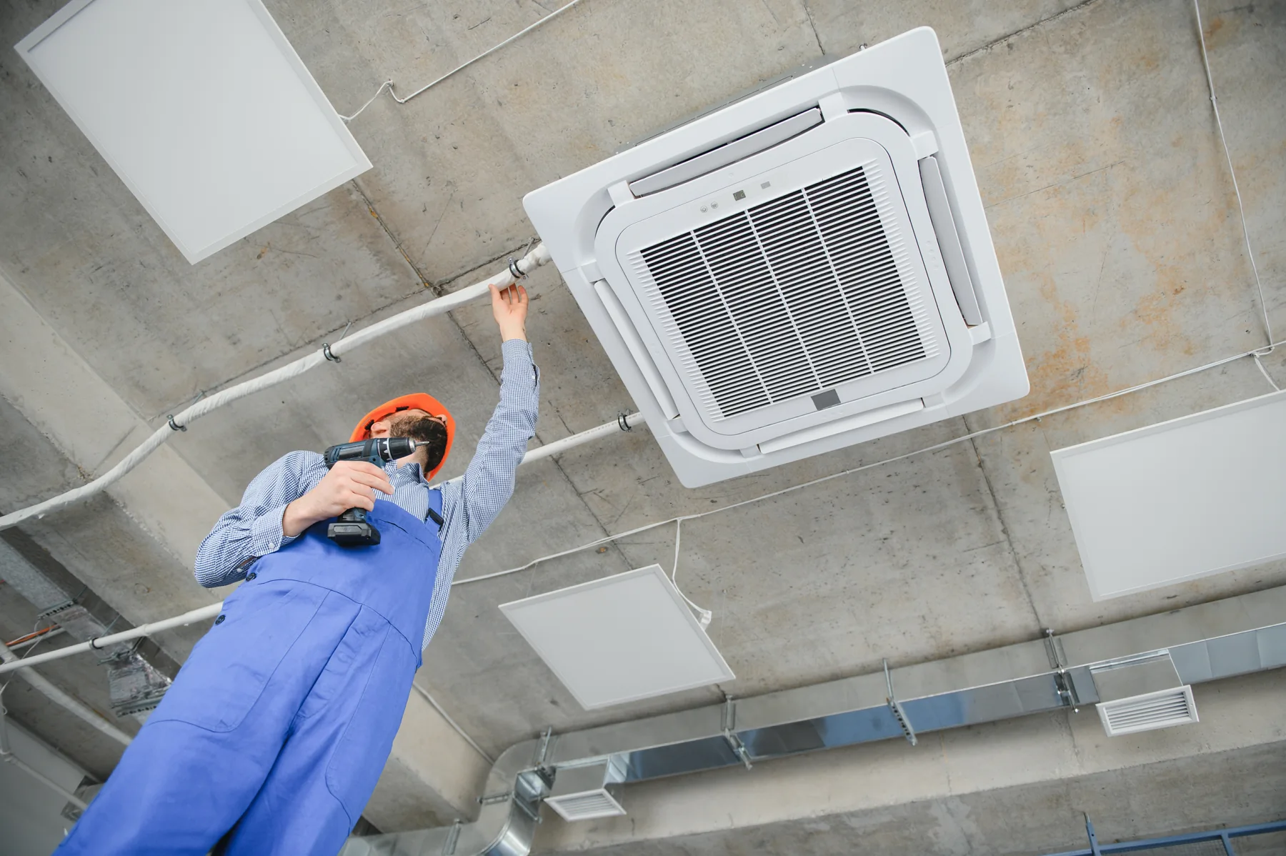 Technician installing a ceiling cassette air conditioner